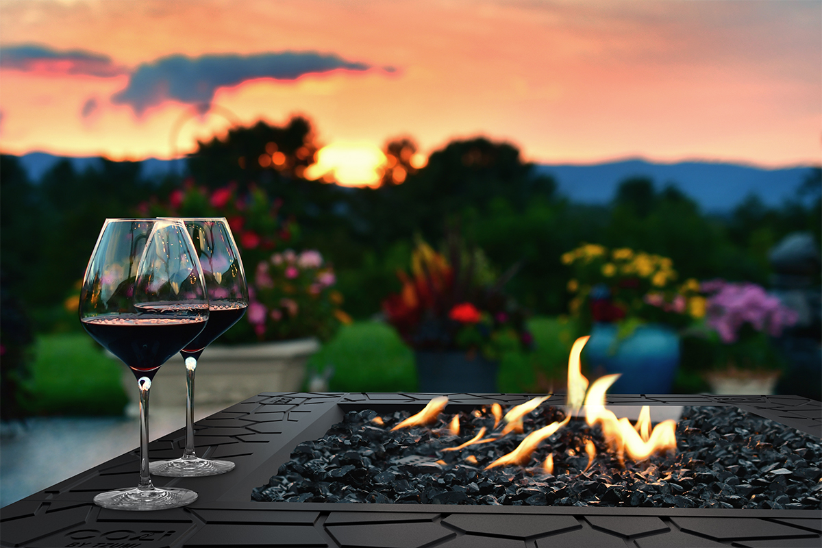 CoZi outdoor fire pit in use with wine glasses on the edge at sunset